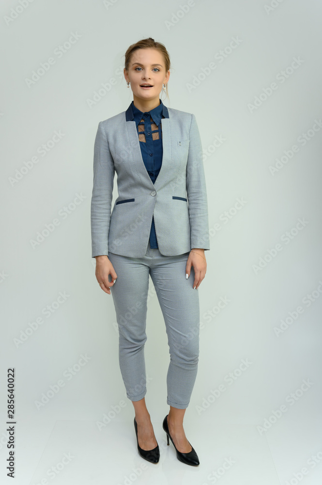 Full length studio portrait of a pretty young woman girl in a business suit on a white background. He stands right in front of the camera, explains, shows hands with emotions. Full length studio portrait of a pretty young woman girl in a business suit on a white background. He stands right in front of the camera, explains, shows hands with emotions.