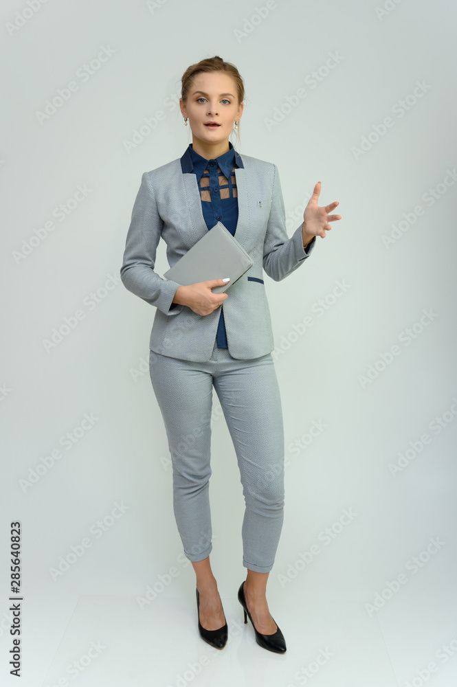 Full length studio portrait of a pretty young woman girl in a business suit on a white background with a folder in hands. He stands right in front of the camera, explains, with emotion. Full length studio portrait of a pretty young woman girl in a business suit on a white background with a folder in hands. He stands right in front of the camera, explains, with emotion.