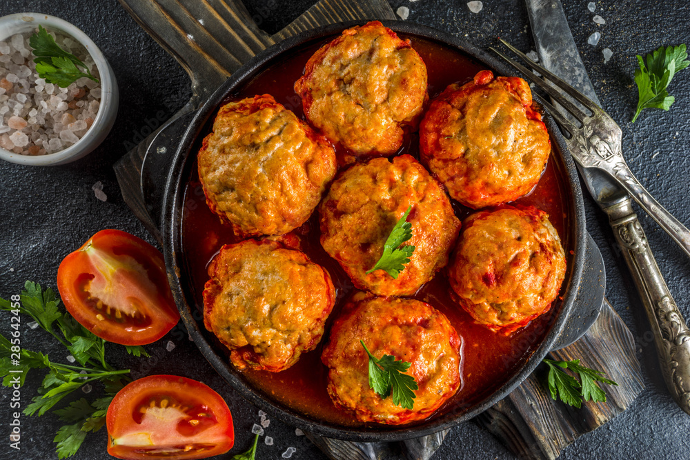 Homemade chicken meatballs in tomato sauce in a frying pan on dark stone or concrete table. Top view copy space Homemade chicken meatballs in tomato sauce in a frying pan on dark stone or concrete table. Top view copy space