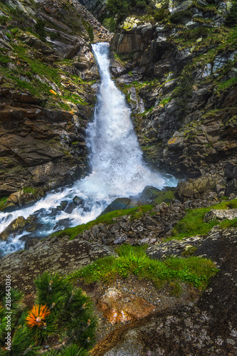 Beautiful waterfall between rocks, foliage & light