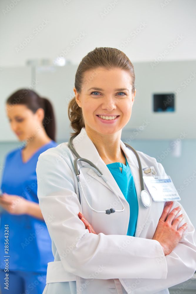 Portrait of confident doctor standing against nurse at clinic Portrait of confident doctor standing against nurse at clinic