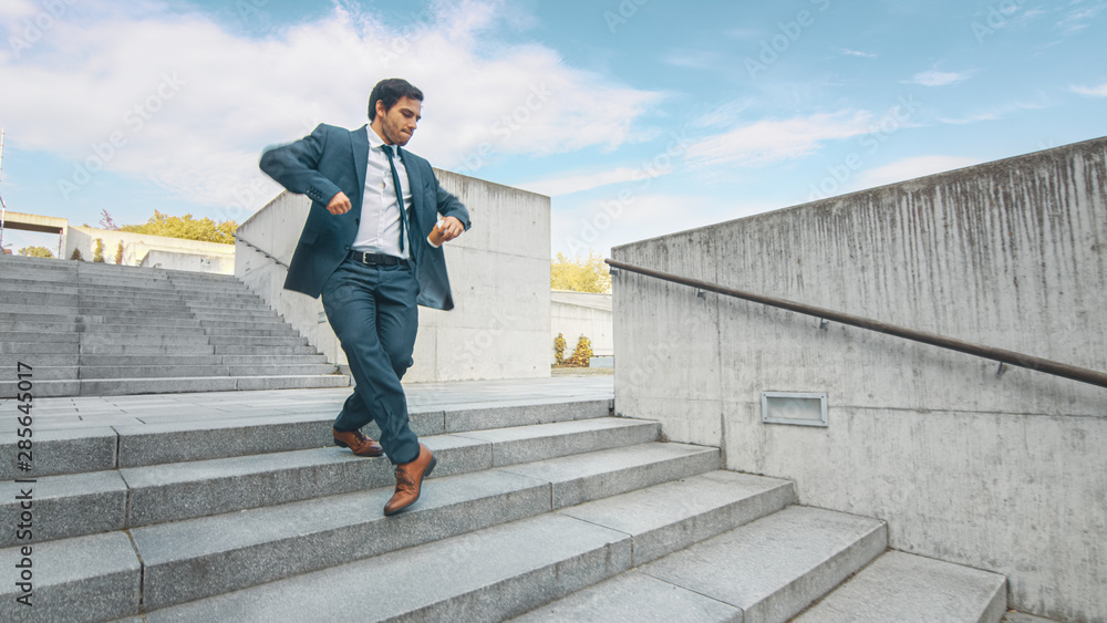 Cheerful and Happy Businessman in a Suit is Holding Coffee and Actively Dancing While Walking Down the Stairs. Scene Shot in an Urban Concrete Park Next to Business Center. Sunny. Cheerful and Happy Businessman in a Suit is Holding Coffee and Actively Dancing While Walking Down the Stairs. Scene Shot in an Urban Concrete Park Next to Business Center. Sunny.