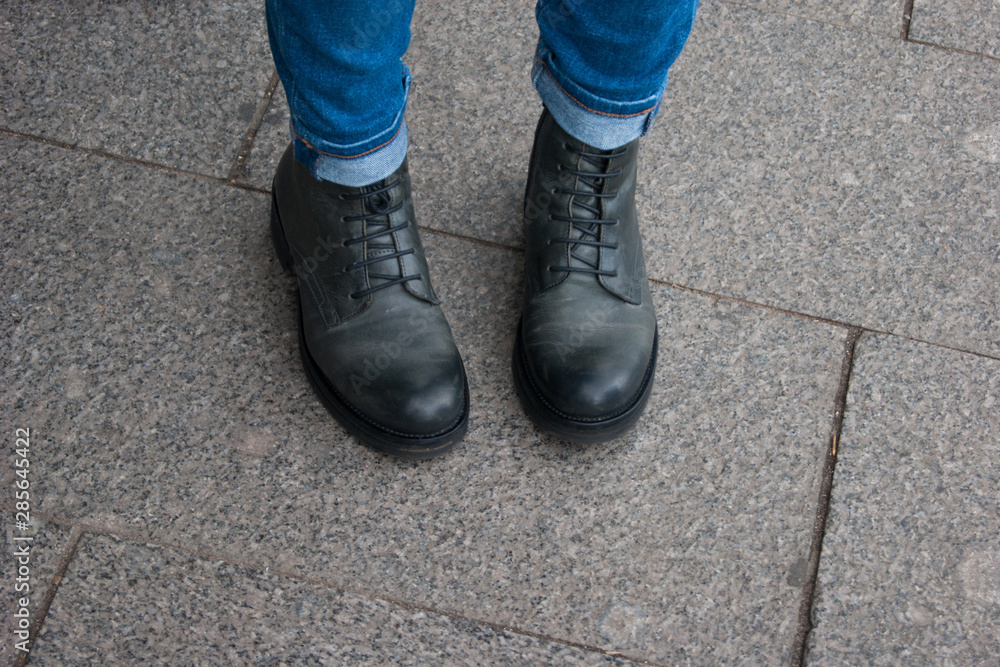 Photo of a part of the human body. Female legs in black unisex boots and jeans stand with socks inside Photo of a part of the human body. Female legs in black unisex boots and jeans stand with socks inside