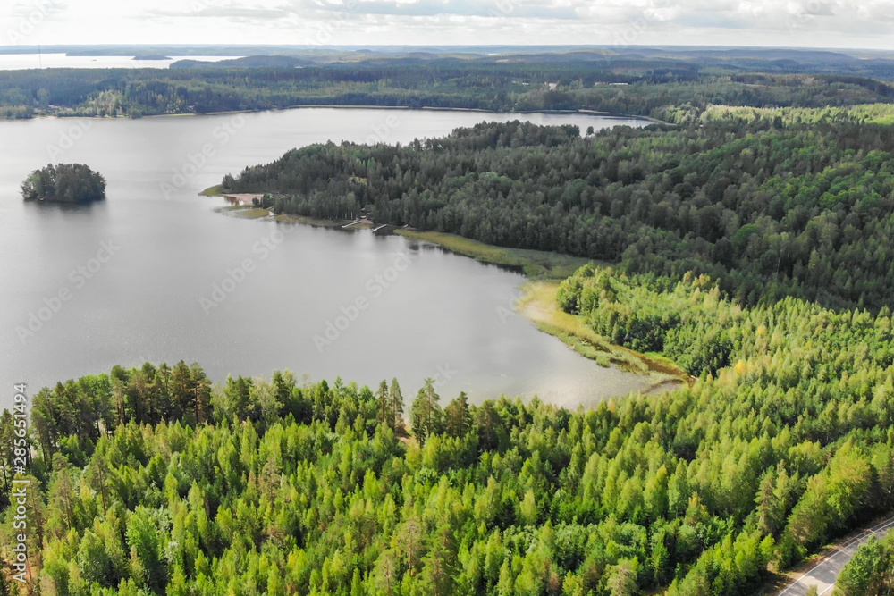 Aerial view of lake with island, road and forest on a summer sunny day in Finland. Drone photography
