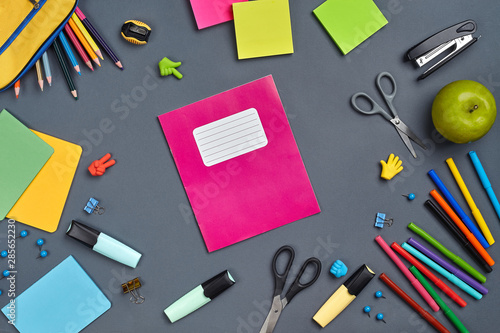 Flat lay photo of workspace desk with school accessories or office supplies on gray background.
