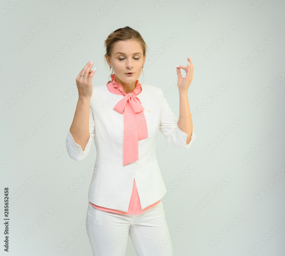 Photo studio portrait of a cute young woman girl in a beautiful suit of white-pink tender color on a white background. He stands right in front of the camera, explains with emotion. Photo studio portrait of a cute young woman girl in a beautiful suit of white-pink tender color on a white background. He stands right in front of the camera, explains with emotion.