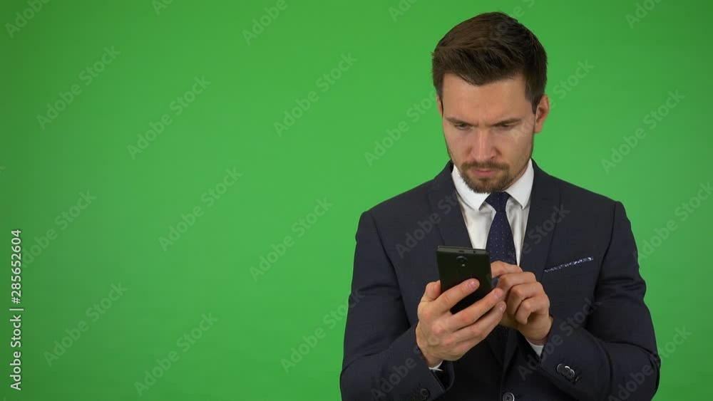 A young handsome businessman works on a smartphone - green screen studio A young handsome businessman works on a smartphone - green screen studio
