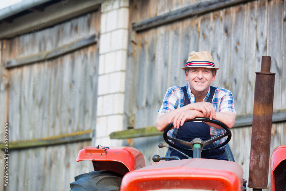 Smiling mature male farmer sitting on tractor
