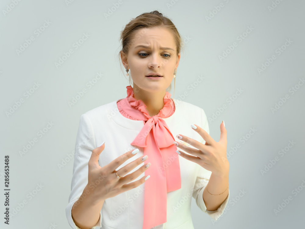 Photo studio portrait of a cute young woman girl in a beautiful suit of white-pink tender color on a white background. He stands right in front of the camera, explains with emotion. Photo studio portrait of a cute young woman girl in a beautiful suit of white-pink tender color on a white background. He stands right in front of the camera, explains with emotion.