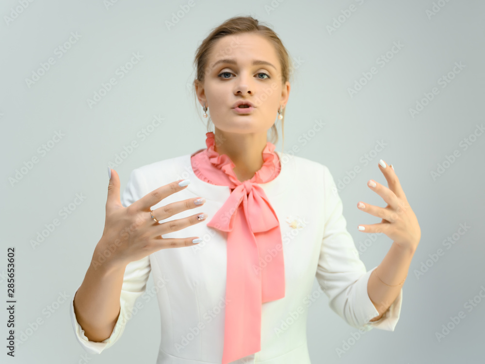 Photo studio portrait of a cute young woman girl in a beautiful suit of white-pink tender color on a white background. He stands right in front of the camera, explains with emotion. Photo studio portrait of a cute young woman girl in a beautiful suit of white-pink tender color on a white background. He stands right in front of the camera, explains with emotion.
