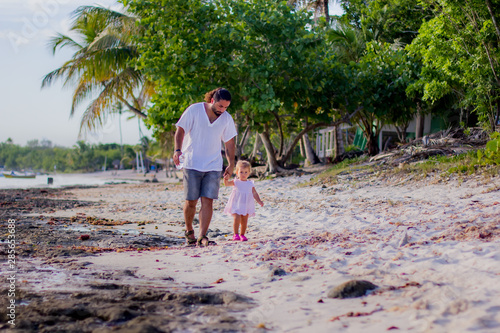 A father and daughter walk along the coast of the Caribbean Sea.