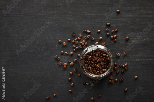 Top view of glass jar filled with coffee beans on dark surface