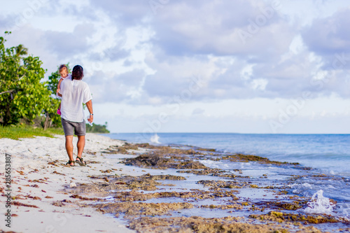 A father and daughter walk along the coast of the Caribbean Sea.