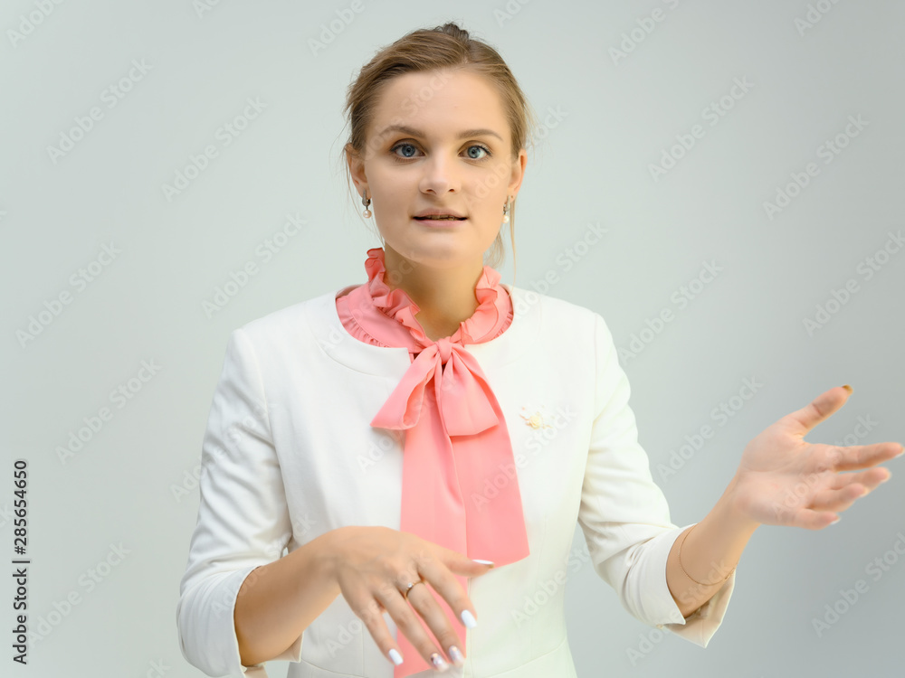 Photo studio portrait of a cute young woman girl in a beautiful suit of white-pink tender color on a white background. He stands right in front of the camera, explains with emotion. Photo studio portrait of a cute young woman girl in a beautiful suit of white-pink tender color on a white background. He stands right in front of the camera, explains with emotion.