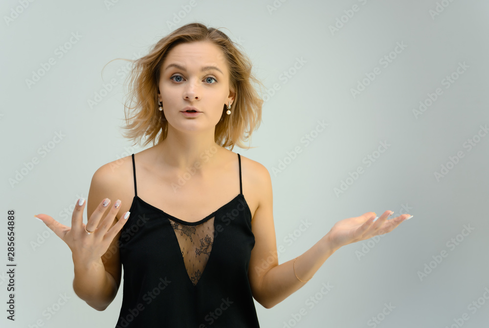 Photo studio portrait of a cute blonde young woman girl in a black blouse on a white background. He stands right in front of the camera, explains with emotion. Photo studio portrait of a cute blonde young woman girl in a black blouse on a white background. He stands right in front of the camera, explains with emotion.