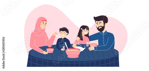 Happy Muslim family enjoying their meal together. Mother in hijab, a father and their son and daughter eating traditional food with tea. Islamic family holiday dinner and spending time at home.