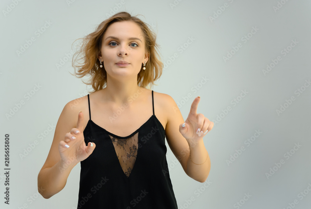 Photo studio portrait of a cute blonde young woman girl in a black blouse on a white background. He stands right in front of the camera, explains with emotion. Photo studio portrait of a cute blonde young woman girl in a black blouse on a white background. He stands right in front of the camera, explains with emotion.