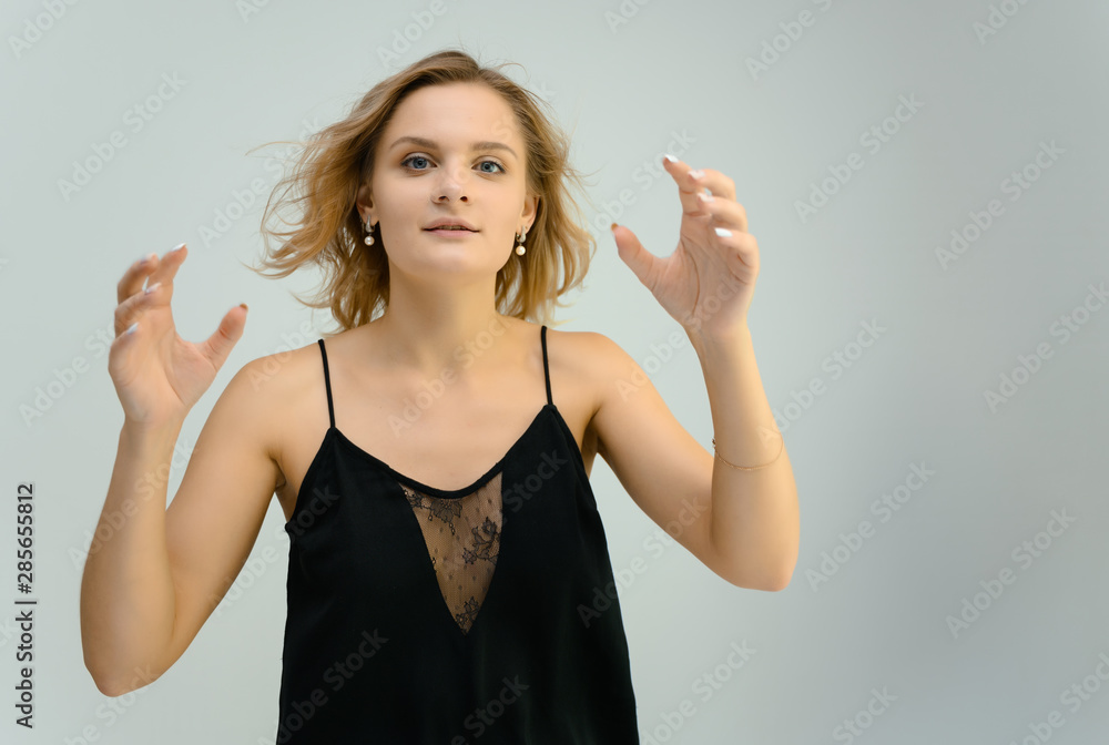 Photo studio portrait of a cute blonde young woman girl in a black blouse on a white background. He stands right in front of the camera, explains with emotion. Photo studio portrait of a cute blonde young woman girl in a black blouse on a white background. He stands right in front of the camera, explains with emotion.