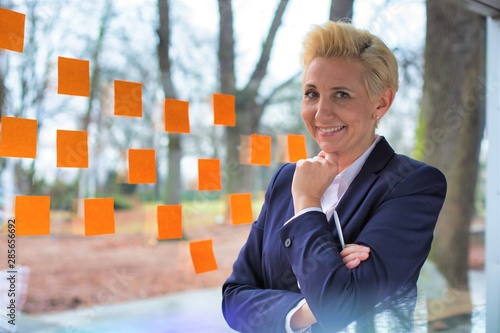 Smiling mature businesswoman standing against windows at office