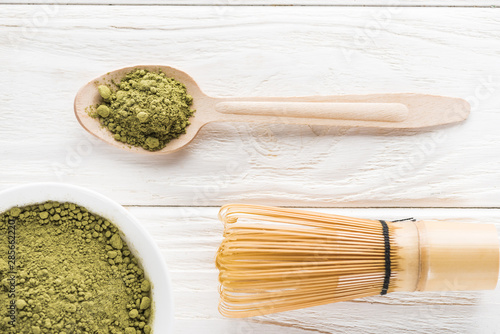 top view of wooden spoon with powder of green matcha tea and whisk