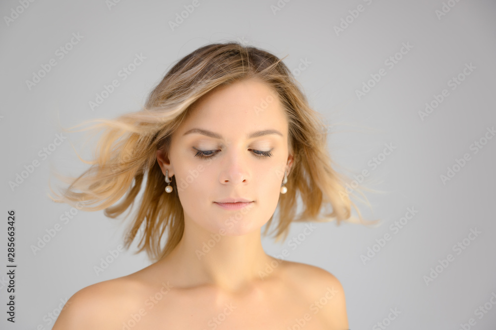 Closeup photo studio portrait of a fashionable pretty blonde young woman girl with beautiful hair on a white background. Standing right in front of the camera. Beauty, cosmetics. Closeup photo studio portrait of a fashionable pretty blonde young woman girl with beautiful hair on a white background. Standing right in front of the camera. Beauty, cosmetics.