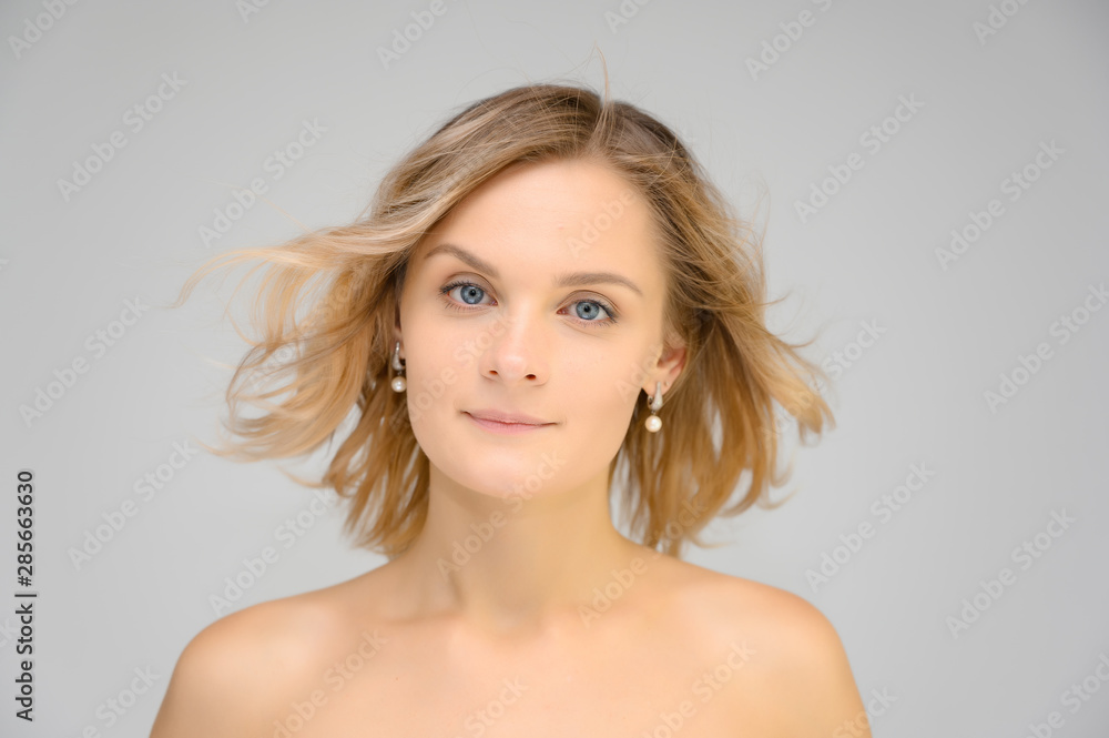 Closeup photo studio portrait of a fashionable pretty blonde young woman girl with beautiful hair on a white background. Standing right in front of the camera. Beauty, cosmetics. Closeup photo studio portrait of a fashionable pretty blonde young woman girl with beautiful hair on a white background. Standing right in front of the camera. Beauty, cosmetics.