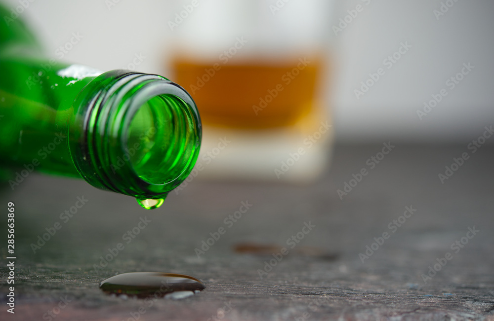 Close up drop of alcohol fail from green bottle.