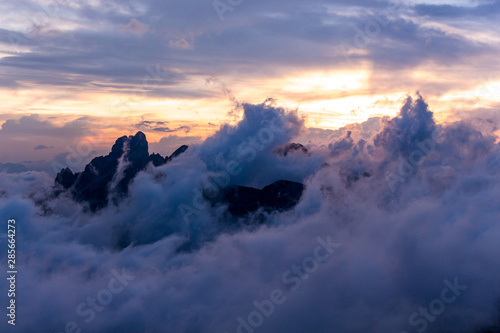Stunning sunset over mountain alpine landscape and high summits or peak of Gosaukamm ridge  Dachstein. Sunset or sunrise colors in Alps  low clouds  motion blurr. Dreamy landscape.