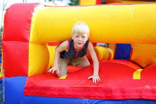 Foto Cute Little Kid Playing on Inflatable Bounce House Obstacle Course at American F