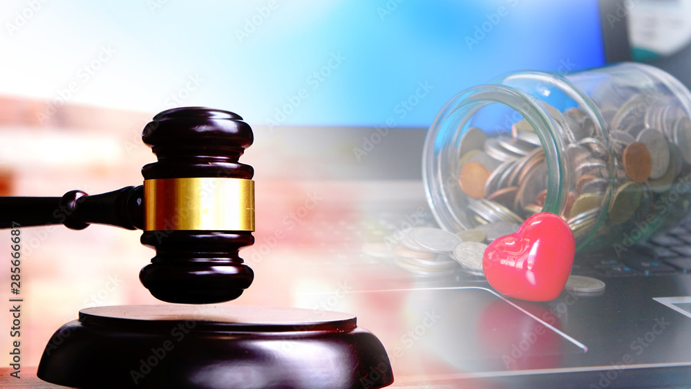 Judge gavel on keyboard laptop with jar money coins and red heart.Prosecution for medical damages or Health Litigation concept. Judge gavel on keyboard laptop with jar money coins and red heart.Prosecution for medical damages or Health Litigation concept.