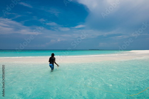Man plants an anchor on a beach in the Maldives