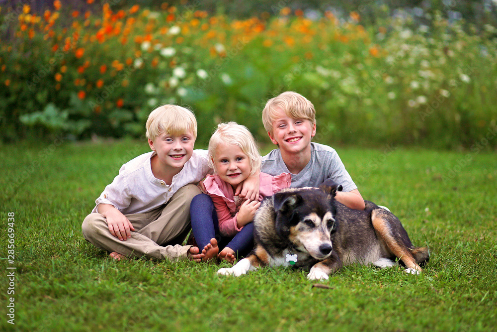Three Happy Cute Little Kids Smiling OUtside with their Old Pet Dog Three Happy Cute Little Kids Smiling OUtside with their Old Pet Dog