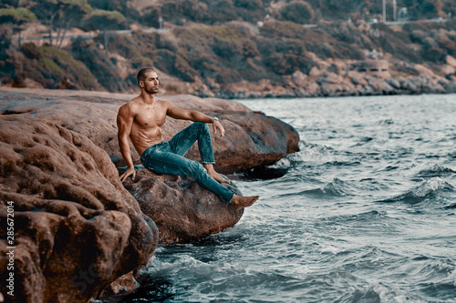 Uomo Body builder in riva al mare con scogli e rocce