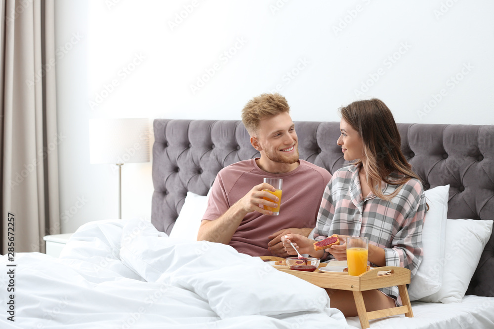 Happy young couple having romantic breakfast in bed at home Happy young couple having romantic breakfast in bed at home