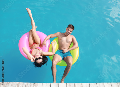 Woman in bikini with boyfriend swimming at resort. Happy young couple