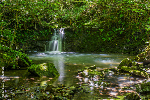 Fototapeta Naklejka Na Ścianę i Meble -  Sun ray lights over a small waterfall in a river in Galdames, Basque Country, Spain