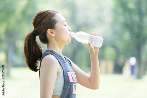 公園で運動（ヨガ）中に水分を補給する女性