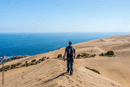 Young caucasian male traveler trekking at Concon sand dune in Vina del Mar, Chile