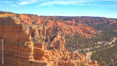 AERIAL: Flying past red cliff revealing road winding into Bryce Canyon in Utah