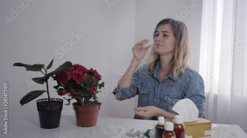 seasonal illness, young beautiful woman indoors suffers and sneezes from allergies to household objects in the room photo