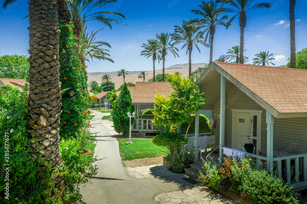 Aerial view of the vacation rental bungalows, houses at the popular Israeli destination kibbutz Nir David, with gorgeous palm trees and red roofs under the blue summer sky