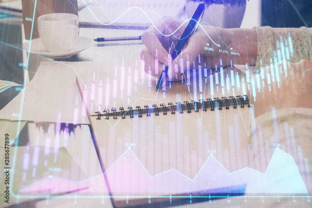 Forex chart hologram on hand taking notes background. Concept of analysis. Double exposure Forex chart hologram on hand taking notes background. Concept of analysis. Double exposure