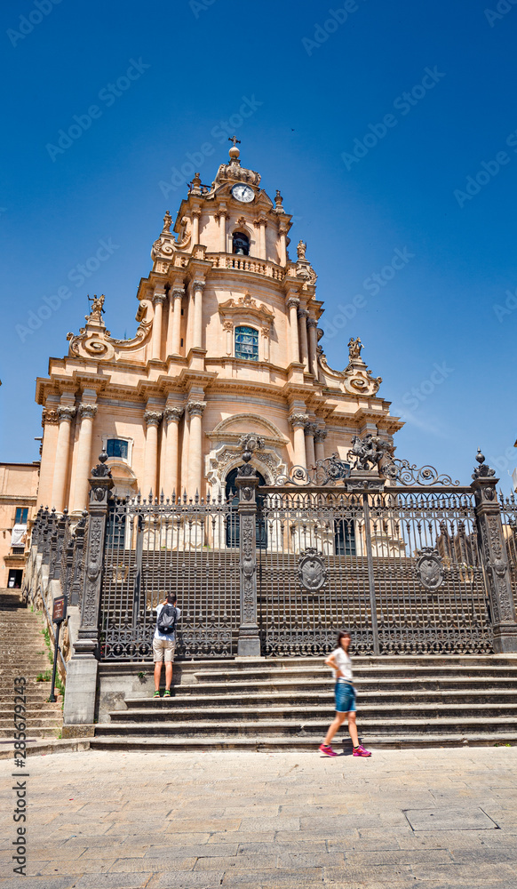 Some tourists visiting the baroque cathedral in the historic center of Ragusa Ibla in Sicily, Italy.