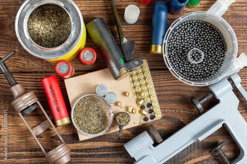 Shotgun shells reloading process with special reload equipment. Powder, bullets, fraction, shells, buckshot on the wooden background.