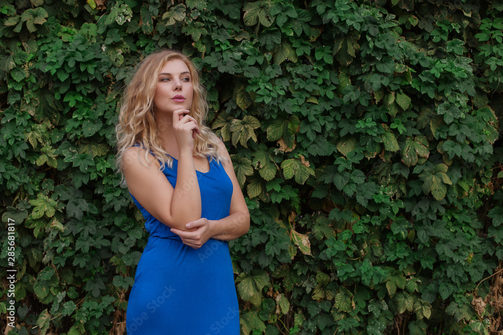 Young beautiful girl on a background of a wall of wild grapes, ponders, thinks an idea. Copy space. Young beautiful girl on a background of a wall of wild grapes, ponders, thinks an idea. Copy space.