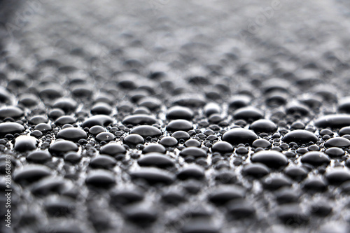 hundreds and thousands of water droplets beading on a gloss black surface of a waxed car photo
