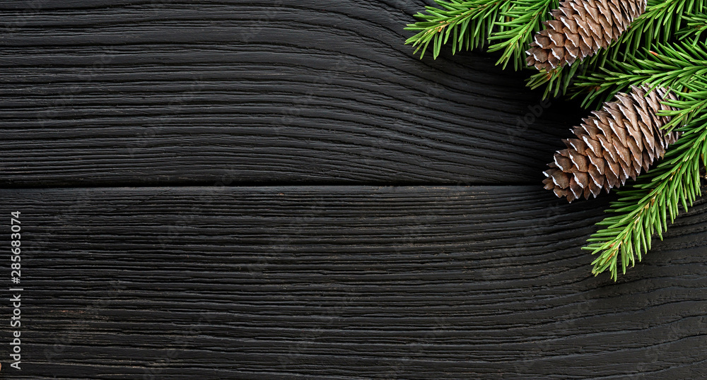 Christmas Fir tree branches with cones on a black wooden background. Christmas Fir tree branches with cones on a black wooden background.