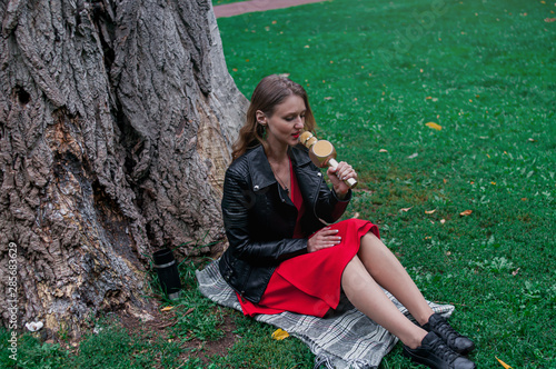 A young girl sits under a tree in the Park and sings into a wireless microphone. The concept of privacy, pleasure, fear of the public