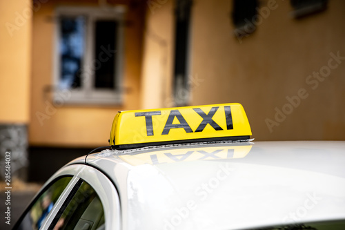 Detail of a TAXI sign on a roof of bright car