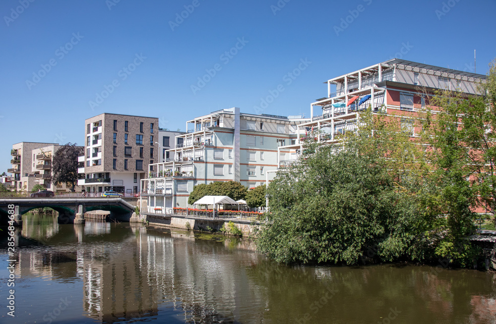 Modern residential buildings in Leipzig scene district Schleussig directly on the river Elster with bridge with blue sky and sunshine